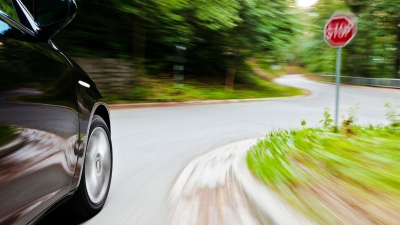 Car speeding towards stop sign on windy road